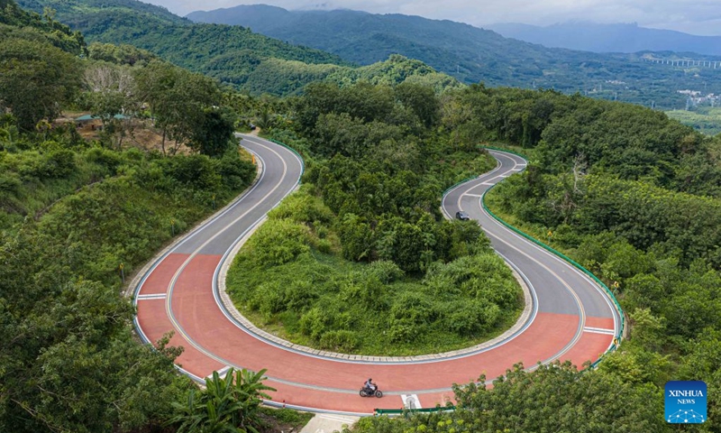 An aerial drone photo taken on Aug. 22, 2026 shows a tourist riding motorcycle at the Baoting section of a scenic ring road surrounding the Hainan Tropical Rainforest National Park in south China's Hainan Province. The scenic ring road surrounding the Hainan Tropical Rainforest National Park passes through nine cities and counties in Hainan, including Lingshui, Baoting, Ledong and Changjiang, with a total length of 466 kilometers. The ring road was officially opened to traffic in December 2024.
This road connects the beautiful scenery of the mountainous areas in the central and southern parts of Hainan Island and builds a green corridor that balances ecological protection and cultural tourism development.
At present, many tourists come to cycle and drive on the road, boosting tourism-related consumption including accommodation, catering, specialty agricultural products, and outdoor culture and tourism along the road. Photo: Xinhua