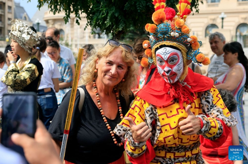 A Romanian poses with an artist during the Open Streets event under the theme of Discover Guangxi to promote the culture and traditions of south China's Guangxi Zhuang Autonomous Region, in Bucharest, Romania, Sept. 12, 2026. (Photo by Cristian Cristel/Xinhua)