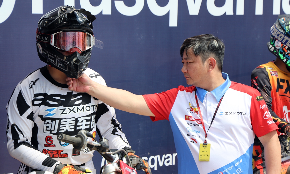 Zhang Xue (right) checks the racing helmet of his son Zhang Qingtian who is competing in the FIM Motocross World Championship Chinese Grand Prix in Shanghai on September 12, 2026 in Shanghai. Photo: VCG