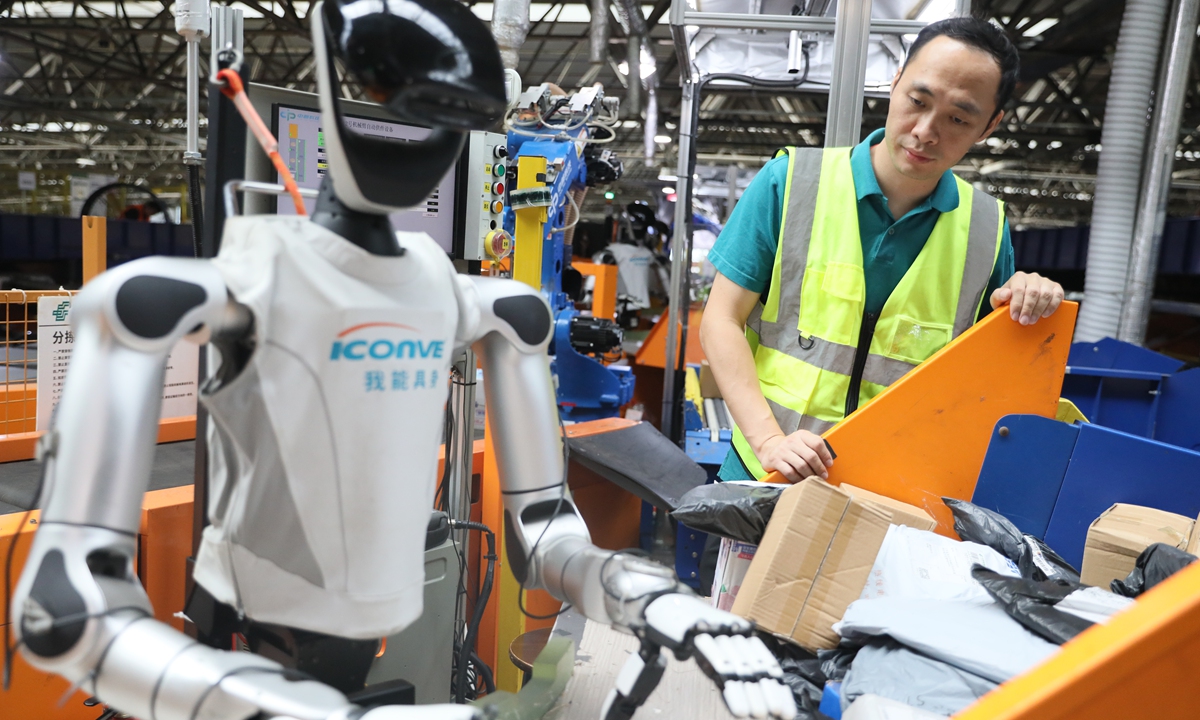 Postal workers check the application of embodied AI robots on a sorting line at the Guangzhou postal district center on September 3, 2026. Photo: VCG