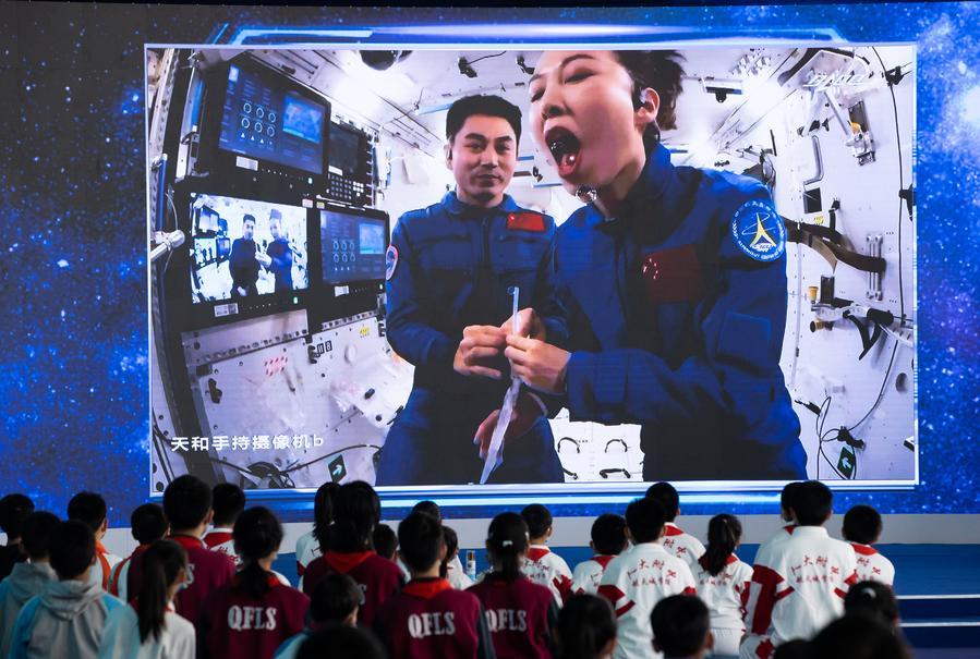 Students watch Wang Yaping (R) demonstrating drinking water in China's space station, at the China Science and Technology Museum in Beijing, capital of China, Dec. 9, 2021. (Xinhua/Jin Liwang)