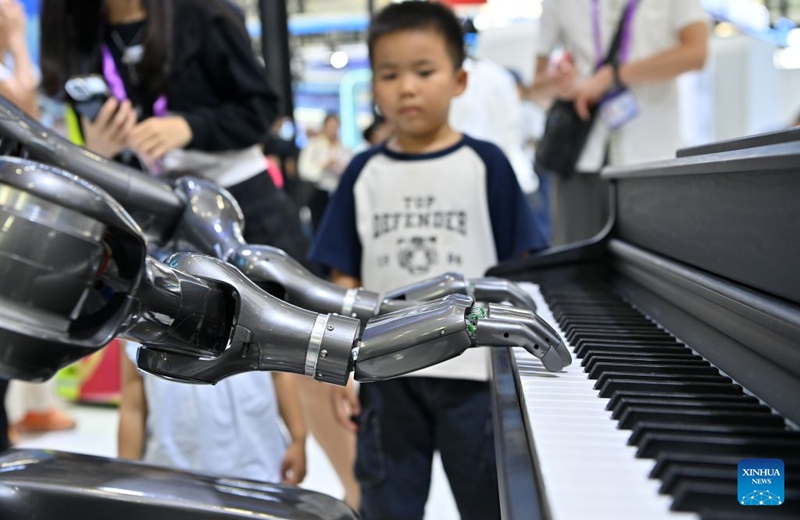 A boy watches a humanoid robot playing the piano at the 23rd China-ASEAN Expo in Nanning, south China's Guangxi Zhuang Autonomous Region, Sept. 19, 2026. Multiple intelligent robots were showcased and demonstrated a variety of skills at the China-ASEAN Expo. (Xinhua/Lu Boan)