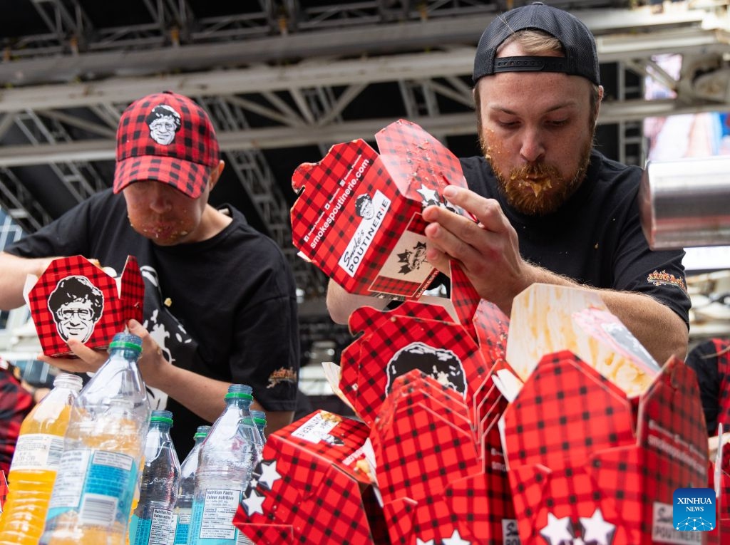 Contestants compete during the 2026 World Poutine Eating Championship in Toronto, Canada, on Sept. 19, 2026. The annual event took place in Toronto on Saturday, with 13 competitive eaters. Joey Chestnut of the United States claimed the title after eating 21.25 pounds of poutine in 10 minutes. (Photo by Zou Zheng/Xinhua)
