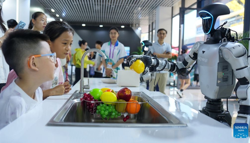 Children watch a humanoid robot picking up fruits at the 23rd China-ASEAN Expo in Nanning, south China's Guangxi Zhuang Autonomous Region, Sept. 19, 2026. Multiple intelligent robots were showcased and demonstrated a variety of skills at the China-ASEAN Expo. (Xinhua/Zhang Ailin)
