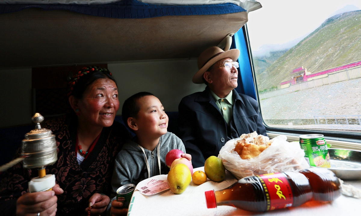 Passengers look out of a train window in Xigaze, Xizang Autonomous Region. Photo: VCG