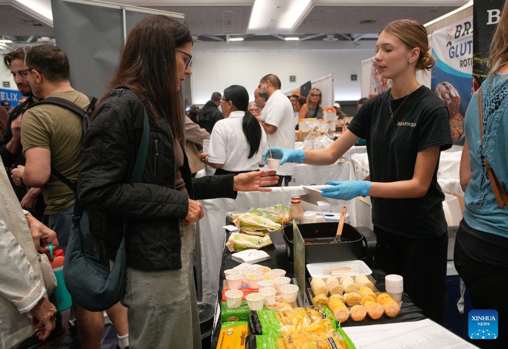 An exhibitor introduces gluten-free products to a visitor at the Gluten Free Expo in Vancouver, British Columbia, Canada, Sept. 20, 2026. The event featured gluten-free food and beverage products, sampling, shopping and educational presentations. (Photo by Liang Sen/Xinhua)