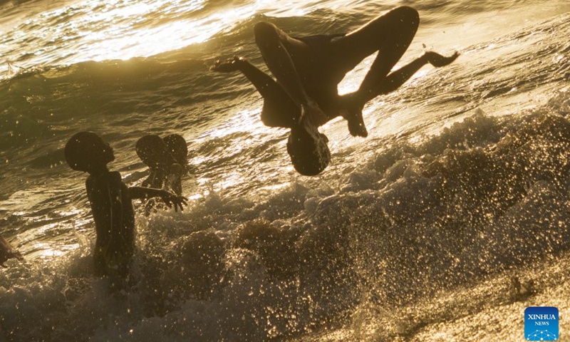 People enjoy leisure time in the sea at the Nouakchott Fishing Port in Nouakchott, Mauritania, Sept. 20, 2026. The Nouakchott Fishing Port, located on the Atlantic coast, is an important fishing hub in Mauritania. The port is known for its rows of traditional wooden pirogues and is a popular gathering place for local residents. (Xinhua/Xie Jianfei)