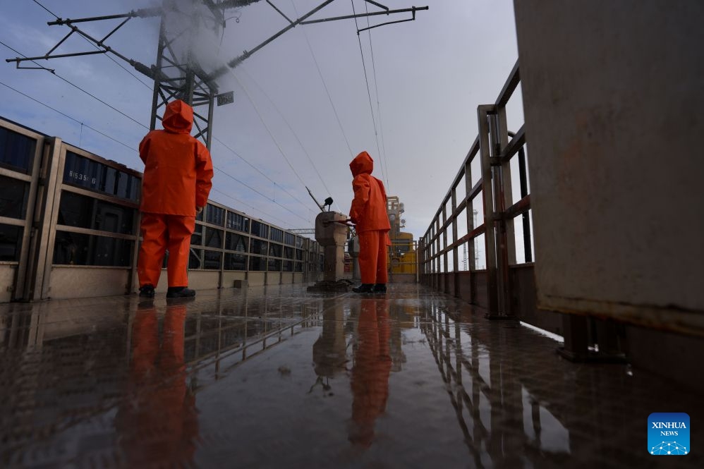 Workers carry out cleaning operations on catenary insulators in Haixi Mongolian and Tibetan Autonomous Prefecture, northwest China's Qinghai Province, Sept. 23, 2026. The Qinghai-Xizang Railway crosses Qairhan salt lake in Haixi Mongolian and Tibetan Autonomous Prefecture of northwest China's Qinghai Province. This 33-kilometer section is frequently hit by strong winds carrying salt dust, which accumulates on catenary insulators and can cause power outages. To ensure safe and reliable railway operations, workers use high-pressure washing equipment to remove salt deposits from catenary insulators along the Qairhan section. (Photo: Xinhua)