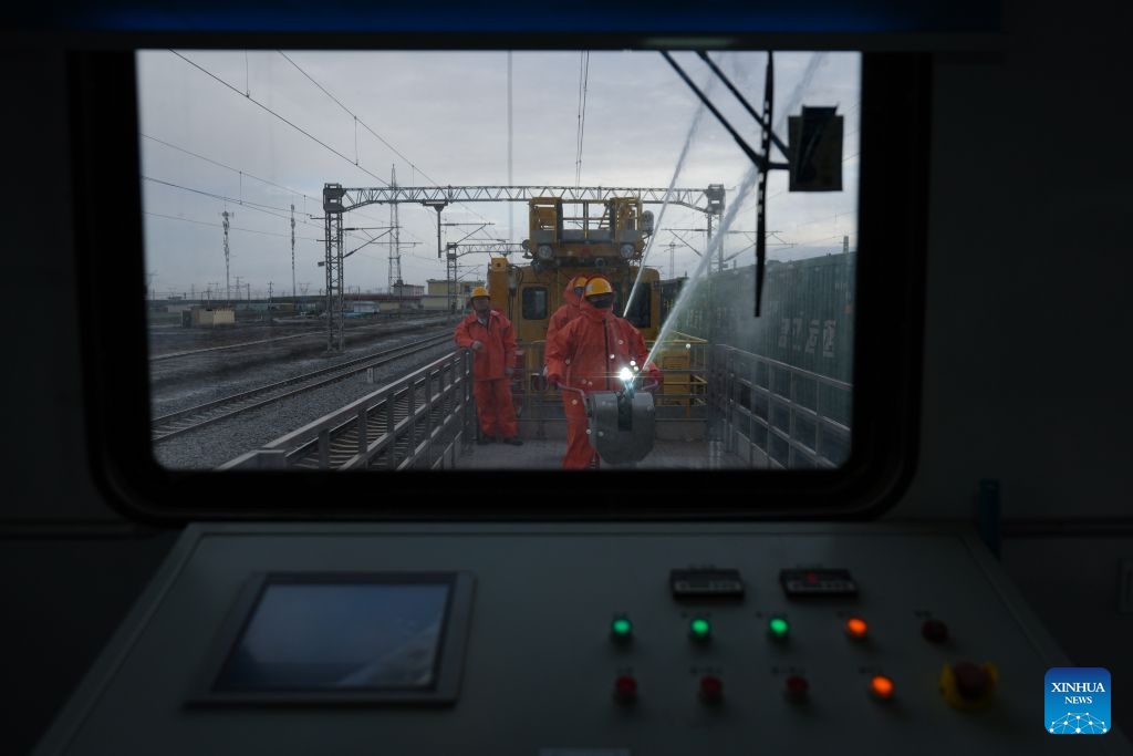 Workers carry out cleaning operations on catenary insulators in Haixi Mongolian and Tibetan Autonomous Prefecture, northwest China's Qinghai Province, Sept. 23, 2026. The Qinghai-Xizang Railway crosses Qairhan salt lake in Haixi Mongolian and Tibetan Autonomous Prefecture of northwest China's Qinghai Province. This 33-kilometer section is frequently hit by strong winds carrying salt dust, which accumulates on catenary insulators and can cause power outages. To ensure safe and reliable railway operations, workers use high-pressure washing equipment to remove salt deposits from catenary insulators along the Qairhan section. (Photo: Xinhua)