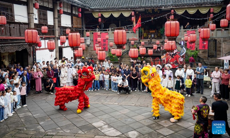 Visitors enjoy a lion dance performance at the ancient town of Zouma in Chongqing, southwest China, Sept. 23, 2026. As the Mid-Autumn Festival and National Day holiday period approaches, the ancient town of Zouma has launched a series of folk cultural activities, including lion dance performances, an intangible cultural heritage market, a Mid-Autumn lantern riddle fair, Hanfu experiences, and Sichuan Opera face-changing performances. Integrating the historical heritage of the town's ancient post road with contemporary folk culture experiences, these activities have attracted numerous local residents and tourists. (Xinhua/Liu Chan)