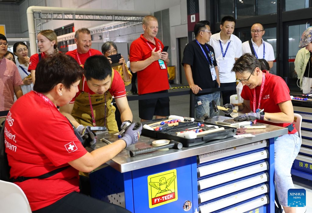 Visitors try to make copperplate engravings during the 48th WorldSkills Competition in east China's Shanghai, Sept. 24, 2026. The 48th WorldSkills Competition, currently being held at the National Exhibition and Convention Center (Shanghai), has attracted a large number of visitors. (Xinhua/Fang Zhe)
