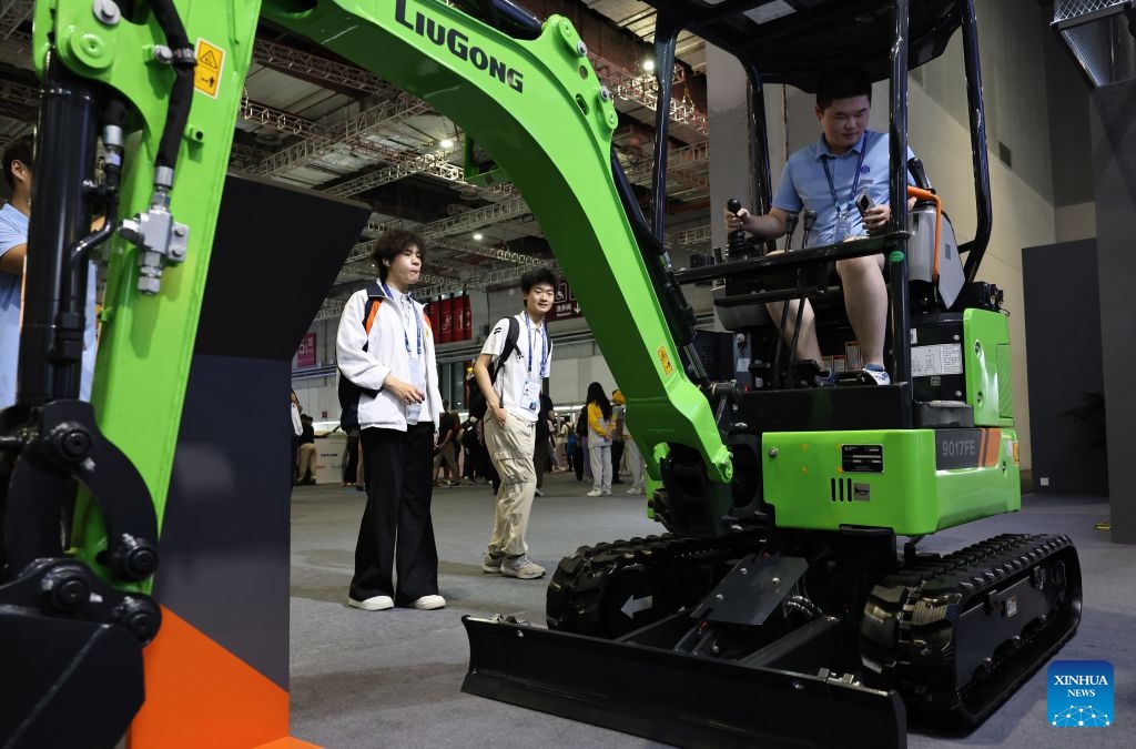 Visitors look at a small excavator exhibited during the 48th WorldSkills Competition in east China's Shanghai, Sept. 24, 2026. The 48th WorldSkills Competition, currently being held at the National Exhibition and Convention Center (Shanghai), has attracted a large number of visitors. (Xinhua/Fang Zhe)