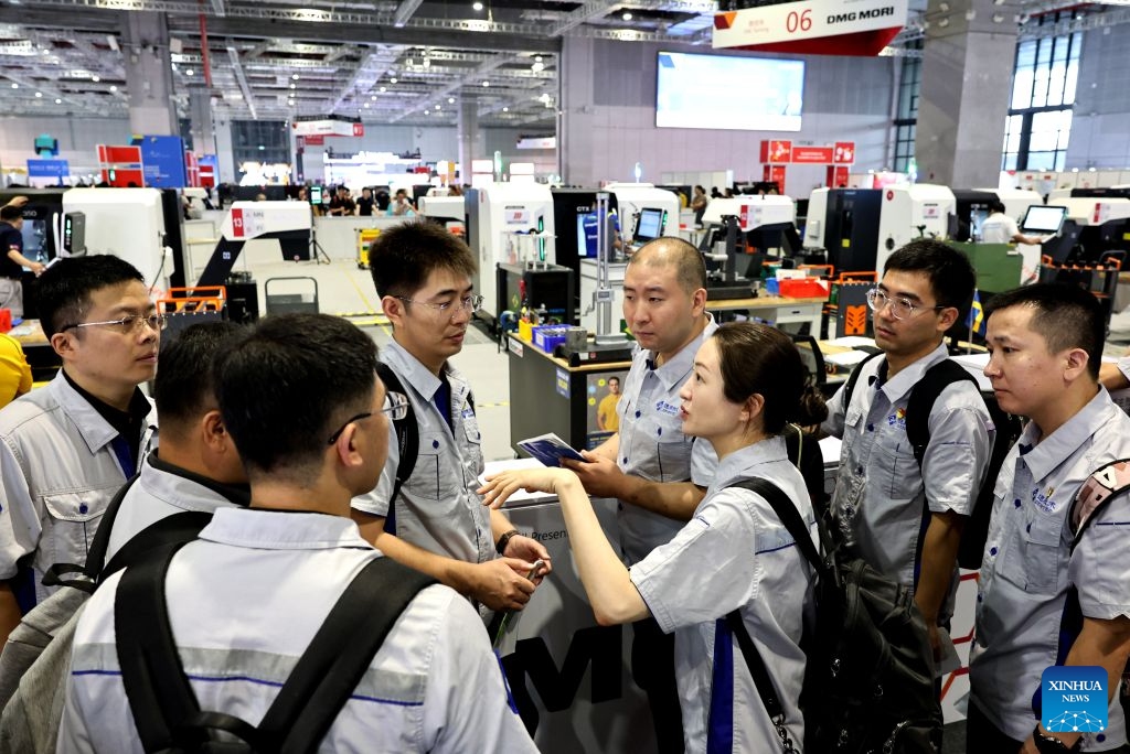 Industrial workers from Genertec communicate outside the venue of the CNC milling event during the 48th WorldSkills Competition in east China's Shanghai, Sept. 24, 2026. The 48th WorldSkills Competition, currently being held at the National Exhibition and Convention Center (Shanghai), has attracted a large number of visitors. (Xinhua/Fang Zhe)