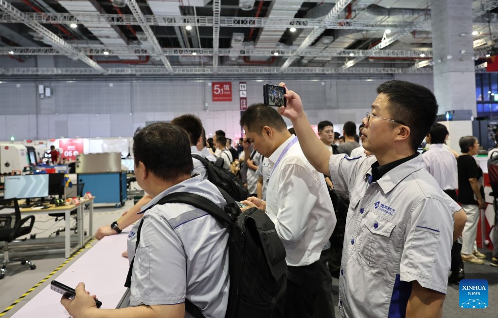 An industrial worker from Genertec films a CNC milling contest during the 48th WorldSkills Competition in east China's Shanghai, Sept. 24, 2026. The 48th WorldSkills Competition, currently being held at the National Exhibition and Convention Center (Shanghai), has attracted a large number of visitors. (Xinhua/Fang Zhe)