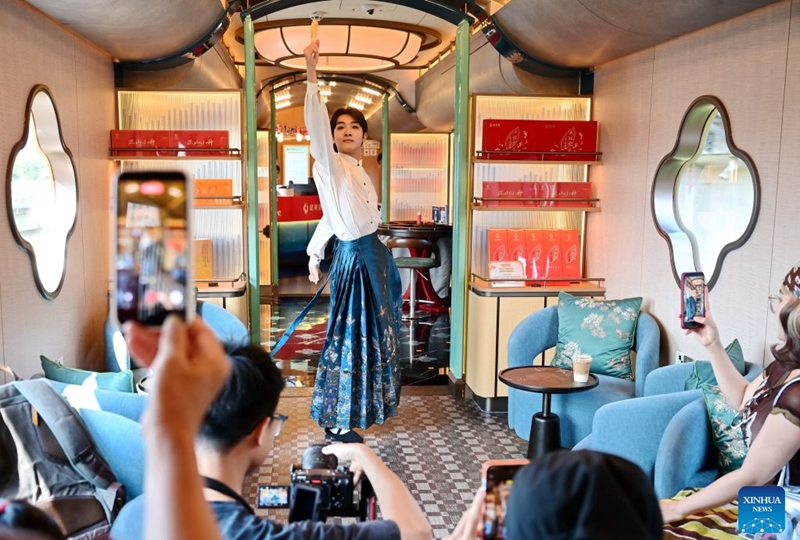 A staff member performs for passengers aboard the Wuyishan National Park-themed sightseeing train on Sept. 24, 2026. With the National Day holiday approaching, the Wuyishan National Park-themed sightseeing train running between Fuzhou Railway Station in southeast China's Fujian Province and Shangrao Railway Station in east China's Jiangxi Province has attracted tourists with its unique travel experience. (Xinhua/Lin Shanchuan)