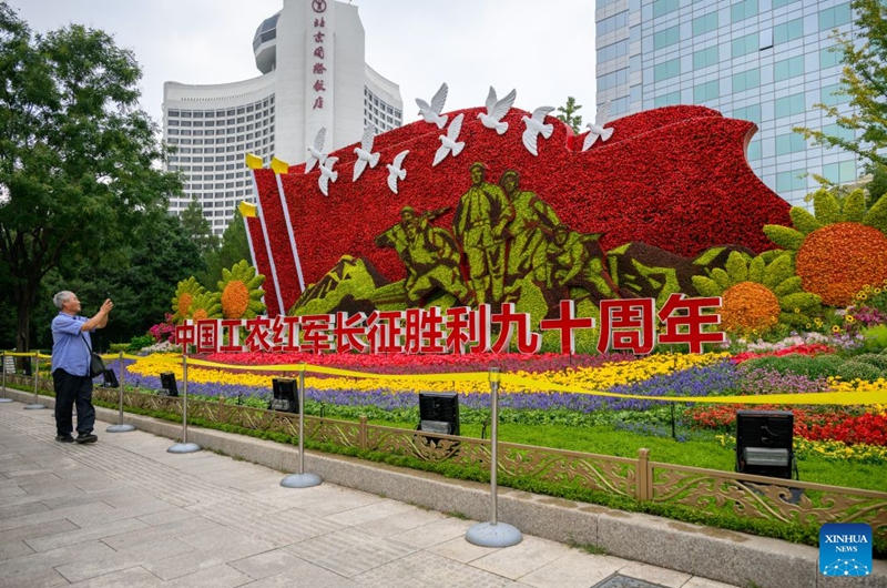 A senior takes pictures of a set of floral decorations at Jianguomen along Chang'an Avenue in Beijing, capital of China, Sept. 25, 2026. Floral decorations have been set up along the Chang'an Avenue in Beijing ahead of China's National Day holidays. (Xinhua/Hu Jingwen)