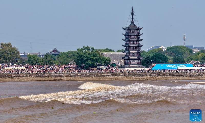 A drone photo taken on Sept. 25, 2026 shows people viewing the tidal bore of the Qiantang River at a park in Haining City, east China's Zhejiang Province. The Mid-Autumn Festival falls on Sept. 25 this year. Tourists came to the Yanguan section of the Qiantang River, the best tide-watching resort, to watch the tide during the best tide-viewing period. (Photo by Wang Zhenyu/Xinhua)