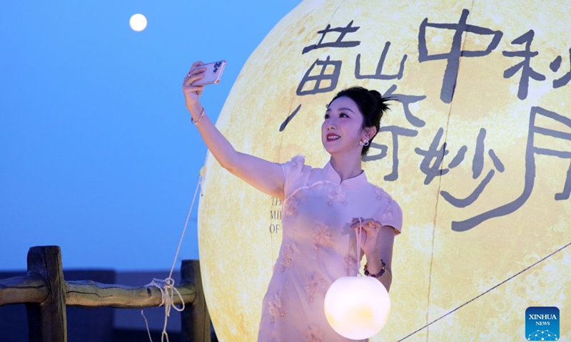 A tourist poses for selfies under the moon during a Mid-Autumn Festival activity in Huangshan Scenic Area, east China's Anhui Province, Sept. 25, 2026. The Mid-Autumn Festival falls on Sept. 25 this year. (Photo by Fan Chengzhu/Xinhua)