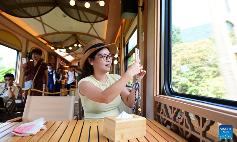 A passenger takes photos of the scenery along the railway aboard the Wuyishan National Park-themed sightseeing train on Sept. 24, 2026. With the National Day holiday approaching, the Wuyishan National Park-themed sightseeing train running between Fuzhou Railway Station in southeast China's Fujian Province and Shangrao Railway Station in east China's Jiangxi Province has attracted tourists with its unique travel experience. (Xinhua/Lin Shanchuan)