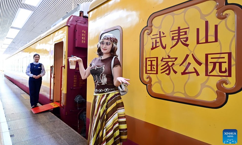 A passenger poses for photos with the Wuyishan National Park-themed sightseeing train at Fuzhou Railway Station in Fuzhou City, southeast China's Fujian Province, on Sept. 24, 2026. With the National Day holiday approaching, the Wuyishan National Park-themed sightseeing train running between Fuzhou Railway Station in southeast China's Fujian Province and Shangrao Railway Station in east China's Jiangxi Province has attracted tourists with its unique travel experience. (Xinhua/Lin Shanchuan)