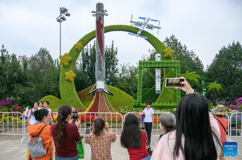 People pose for photos in front of a set of floral decorations at Dongdan area along Chang'an Avenue in Beijing, capital of China, Sept. 25, 2026. Floral decorations have been set up along the Chang'an Avenue in Beijing ahead of China's National Day holidays. (Xinhua/Hu Jingwen)