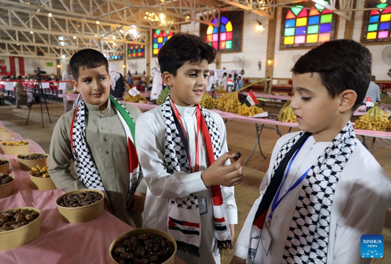 Boys taste dates displayed at an annual date festival in Salahuddin Province, Iraq, on Sept. 25, 2026. (Xinhua/Khalil Dawood)