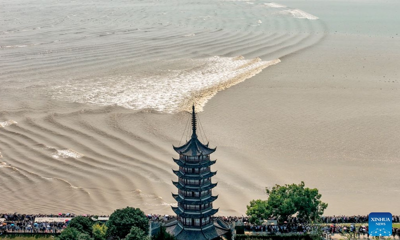 An aerial drone photo taken on Sept. 25, 2026 shows people viewing the tidal bore of the Qiantang River at a park in Haining City, east China's Zhejiang Province. The Mid-Autumn Festival falls on Sept. 25 this year. Tourists came to the Yanguan section of the Qiantang River, the best tide-watching resort, to watch the tide during the best tide-viewing period. (Photo by Wang Zhenyu/Xinhua)