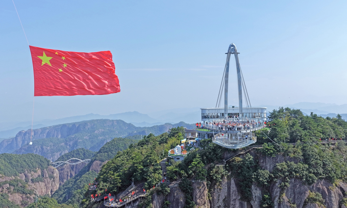 Tourists sing the patriotic song Ode to the Motherland under a massive national flag of China, at Shenxianju Scenic Area in Xianju County, Taizhou, East China's Zhejiang Province, on September 27, 2026, marking the upcoming 77th anniversary of the founding of the People's Republic of China. Photo: VCG