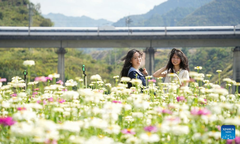 Tourists pose for a photo amid flowers in Kaili, Qiandongnan Miao and Dong Autonomous Prefecture, southwest China's Guizhou Province, Sept. 26, 2026. Chinese people are on a three-day holiday for the Mid-Autumn Festival, which fell on Sept. 25 this year. (Photo by Cai Xingwen/Xinhua)