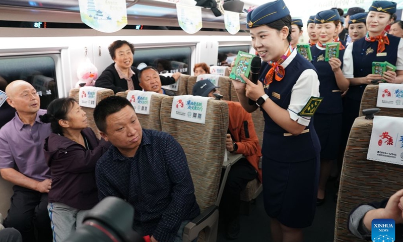 Train attendants interact with passengers on G9997, the first train of the Xi'an-Ankang high-speed railway, in northwest China's Shaanxi Province, Sept. 28, 2026. The Xi'an-Ankang high-speed railway was officially put into operation on Monday, cutting the railway travel time between Xi'an and Ankang to less than one hour. Spanning about 171 kilometers and with a design speed of 350 kilometers per hour, the railway runs through the cities of Xi'an, Shangluo and Ankang in Shaanxi Province and has five stations along the line. (Xinhua/Shao Rui)