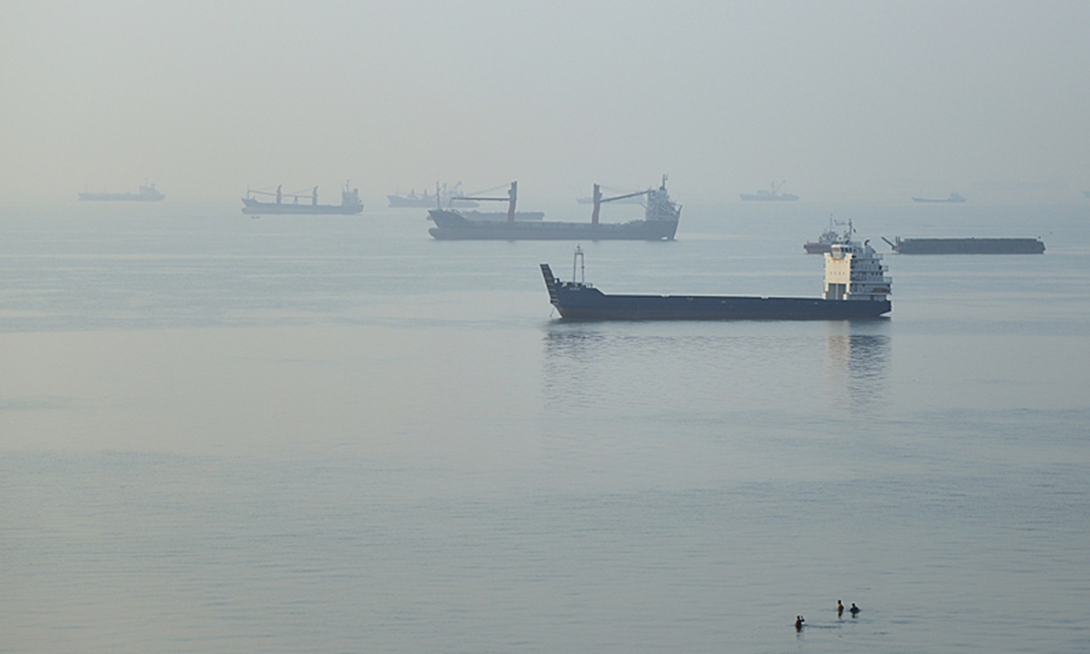People wade in the water as cargo ships are anchored in the Strait of Hormuz off Bandar Abbas, Iran, on September 28, 2026. Photo: VCG