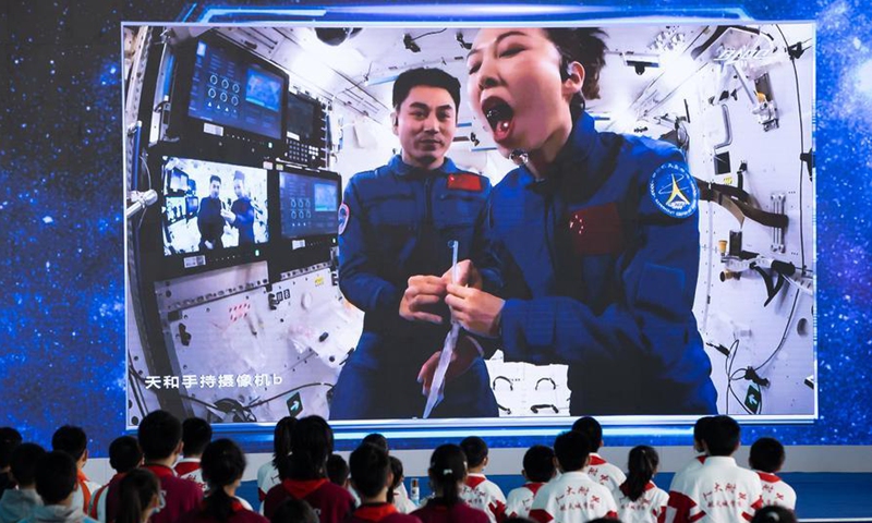 Students watch Wang Yaping (R) demonstrating drinking water in China's space station, at the China Science and Technology Museum in Beijing, capital of China, Dec. 9, 2021. (Xinhua/Jin Liwang)
