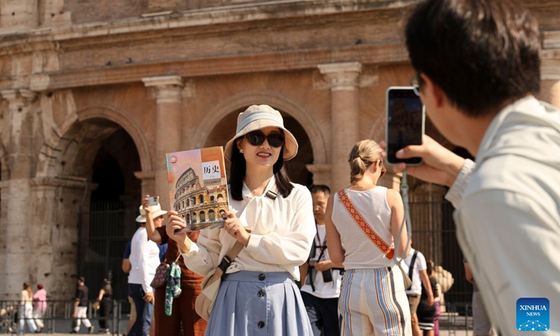 A Chinese tourist poses with a Chinese high school textbook with cover of the Colosseum in front of the Colosseum in Rome, Italy, Oct. 4, 2026. (Xinhua/Li Jing)