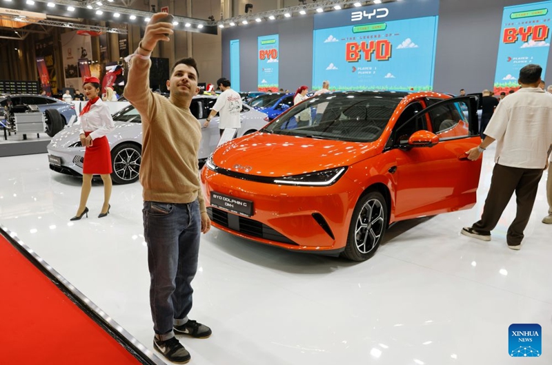 A visitor poses for photo before a car model produced by Chinese producer BYD during the first day of Bucharest Auto Show & Accessories in Bucharest, Romania, Oct. 6, 2026. Photo: Xinhua