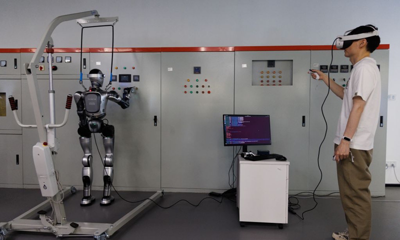 An employee operates a humanoid robot to repair electrical equipment at an embodied AI training base in Beijing, capital of China, on May 29, 2026.  (Xinhua/Jin Liwang)