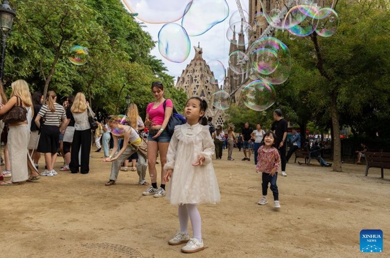 Chinese tourists play with soap bubbles near the Sagrada Familia Basilica in Barcelona, Spain, Oct. 6, 2026. Photo: Xinhua