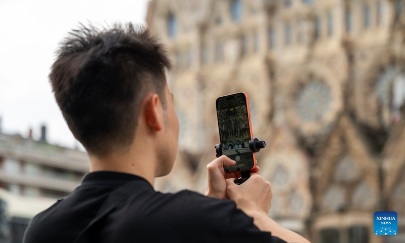A Chinese tourist takes photos in front of Sagrada Familia Basilica in Barcelona, Spain, Oct. 6, 2026. Photo: Xinhua