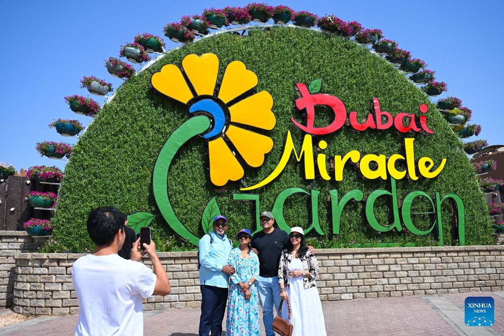 People pose for a group photo at Dubai Miracle Garden in Dubai, the United Arab Emirates, Oct. 8, 2026. Dubai Miracle Garden opened Thursday to the public for its 15th season. Featuring colorful floral displays and large-scale installations, the garden is a popular tourist attraction in Dubai. (Xinhua/Wang Zecong)