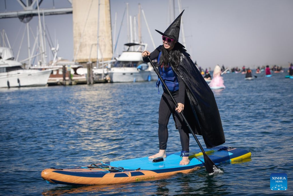 A participant dressed as a witch paddles along the waterfront during the 6th Witchilano Paddle in Vancouver, British Columbia, Canada, Oct. 3, 2026. The annual event took place on Saturday, bringing together hundreds of costumed paddlers to celebrate the upcoming Halloween on the water. (Photo by Liang Sen/Xinhua)