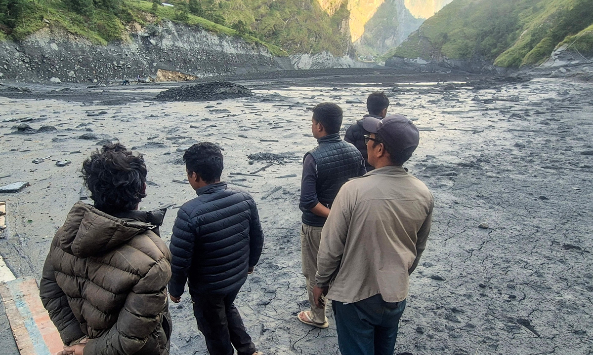 Locals stand over sludge along the banks of the Budhi Gandaki River in Nepal's Gorkha district on October 12, 2026, a day after a flash flood caused by a dry landslide. The flood swept away houses, leaving at least five people missing, officials said. Photo: VCG