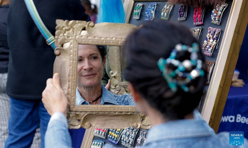 A woman tries on a traditional Scottish headpiece during the Canberra Highland Gathering in Canberra, Australia, on Oct. 10, 2026. The Scottish cultural event featuring traditional sports, bagpipe and drum performances, dance and traditional food was held in Canberra on Saturday. (Photo by Chu Chen/Xinhua)