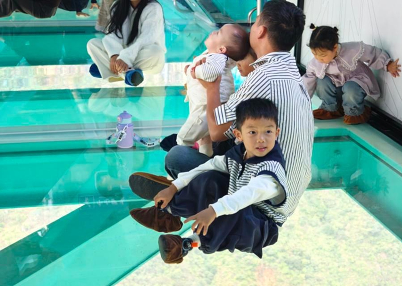 Tourists view the scenery at the glass observation hall on the Huajiang Grand Canyon Bridge in southwest China's Guizhou Province, Oct. 5, 2026. (Xinhua)