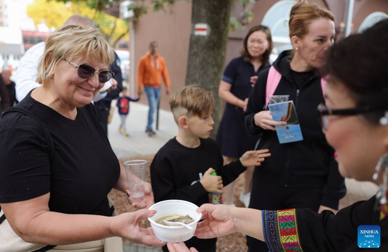 A staff member serves a Chinese dish to a visitor during the 2026 Siofok Fish Festival in Siofok, Hungary, Oct. 10, 2026. Sit on the southern shore of Lake Balaton, Hungary's largest lake, Siofok is one of the country's leading lakeside holiday destinations. The city's annual fish festival is a major autumn event, with its 13th edition taking place on Oct. 9-11, 2026. (Xinhua/Hu Zhixuan)