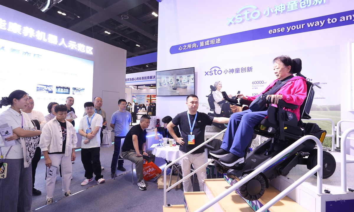 A visitor tries out a stair-climbing robot at the 12th Beijing International Ageing Industry Expo in Beijing on October 11, 2026. Over 400 exhibitors showcased products spanning the full spectrum of the elder care industry, ranging from smart senior care and age-friendly goods to healthcare, senior tourism, and elderly care finance, during the expo, which was held from Friday to Sunday. Photo: VCG