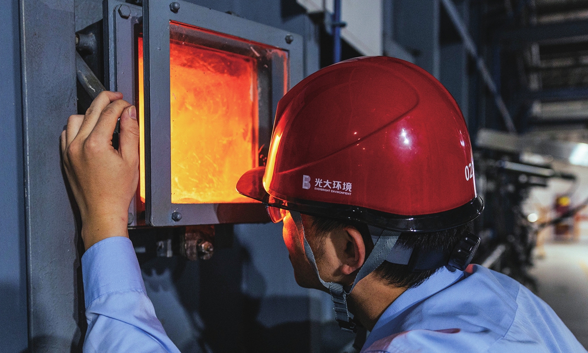 A technician at the waste treatment plant monitors the flames inside the incinerator, where the flame temperature exceeds 900 C. Photo: Li Hao/GT