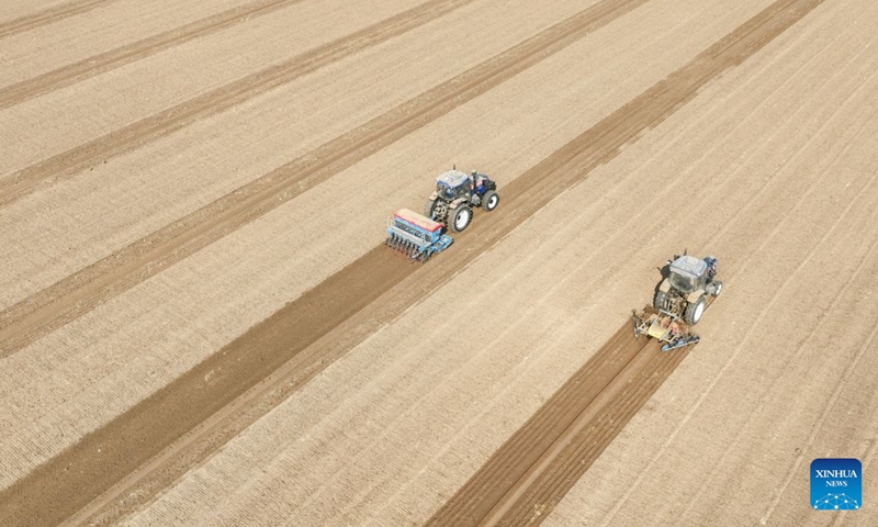 An aerial drone photo taken on Oct. 10, 2026 shows farm machinery sowing wheat in the fields at Weiqiao Town in Zouping City, east China's Shandong Province. As autumn sets in, farmers across China make the most of the farming season to work to ensure stable grain production. (Photo by Dong Naide/Xinhua)