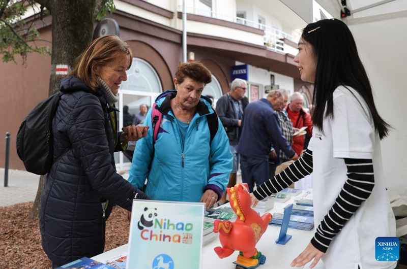 A staff member introduces Chinese tourism to visitors during the 2026 Siofok Fish Festival in Siofok, Hungary, Oct. 10, 2026. Sit on the southern shore of Lake Balaton, Hungary's largest lake, Siofok is one of the country's leading lakeside holiday destinations. The city's annual fish festival is a major autumn event, with its 13th edition taking place on Oct. 9-11, 2026. (Xinhua/Hu Zhixuan)