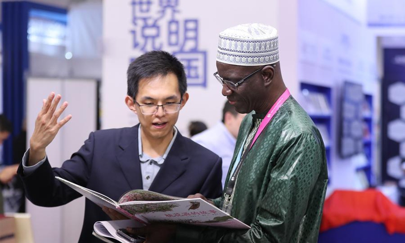 A reader (R) talks to a staff member at the Chinese joint exhibition booth of the Frankfurt Book Fair in Frankfurt, Germany, Oct. 7, 2026. (Xinhua/Du Zheyu)