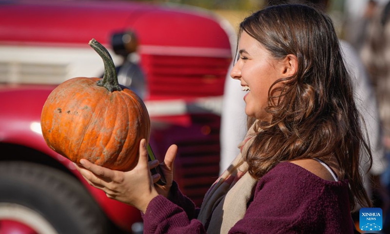 A woman holds a pumpkin at a farm in Richmond, British Columbia, Canada, Oct. 11, 2026. Visiting pumpkin patches is a popular autumn activity in Canada, attracting families to local farms to enjoy the harvest season. (Photo by Liang Sen/Xinhua)