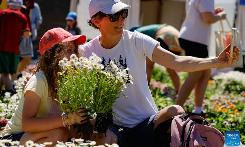 People take a selfie during the Great Big Bulb Dig event at Commonwealth Park in Canberra, Australia, on Oct. 12, 2026. The Great Big Bulb Dig, held annually following the end of the Floriade flower festival, attracted a large number of visitors to dig up and take home flower bulbs and annuals from the festival's display beds. (Photo by Chu Chen/Xinhua)